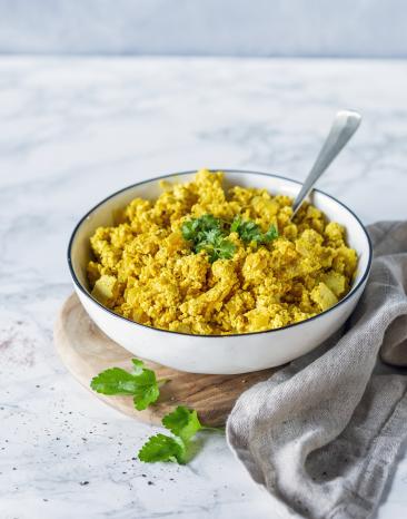 Rührei mit Petersilie in einer hellen Schale auf einem Marmoruntergrund.