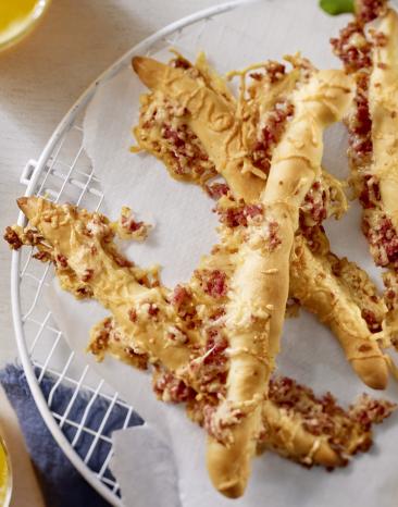 Knusprige Käsestangen mit kleinen Salamistücken.