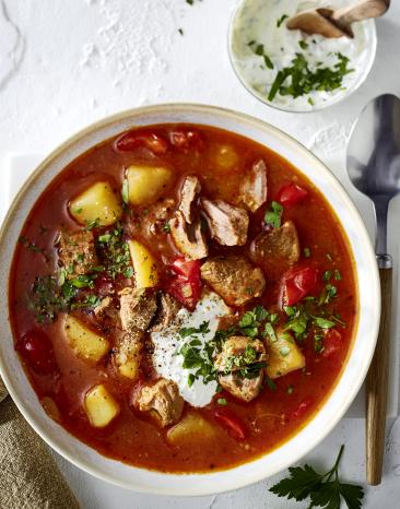 Eintopf angerichtet in einem hellen, tiefen Teller mit Löffel