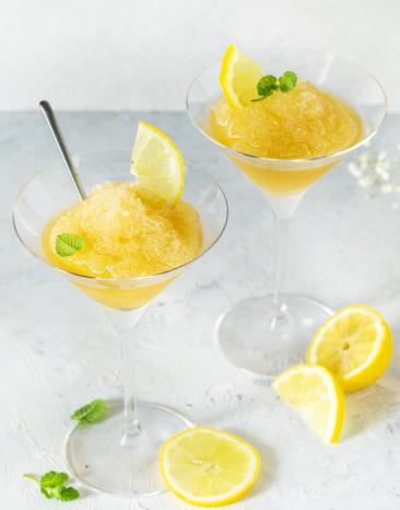 Granita Siciliana serviert in Cocktailgläsern garniert mit Zitronen.