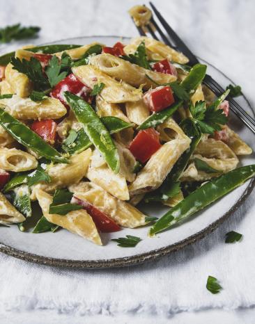 Penne mit Zuckerschoten und Paprika mit cremiiger Sauce auf Teller.