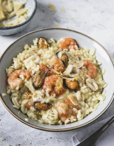 Risotto mit Meeresfrüchten auf Teller mit Parmesan bestreut.