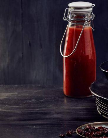 Fruchtige BBQ-Sauce in zwei Henkelflaschen sowie einer Schale auf einem Tisch