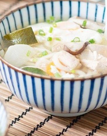 Japanische Udon-Nudelsuppe in einer Suppenschale, daneben Essstäbchen