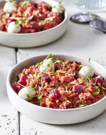 Rote Bete Risotto mit Mozzarella-Perlen in zwei hellen Schüsseln angerichtet.