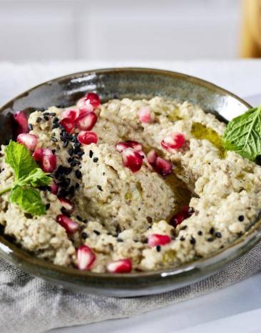 Creme aus Aubergine in einer Schale getoppt von Granatapfelkernen