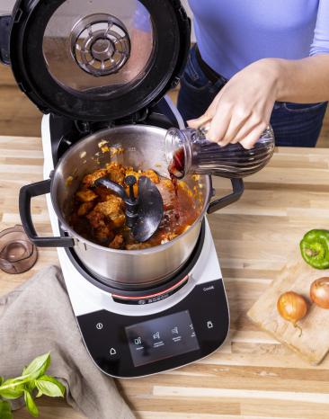 Rotwein wird zu Gulasch in den Cookit gegossen.