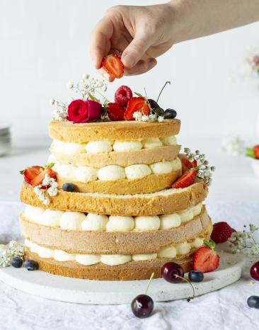 Hochzeitstorte wird mit Beeren dekoriert.
