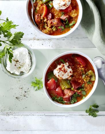 Spanische Linsensuppe mit Frischkäse in einer Schale.