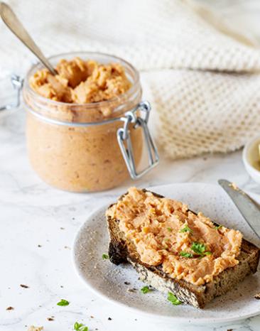 Einfache Teewurst in einem Einmachglas und aufgestrichen auf einer Scheibe Brot.