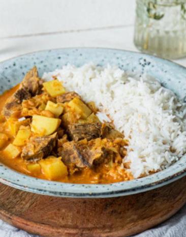 Portion des Massaman Currys mit Reis als Beilage in einem tiefen Teller