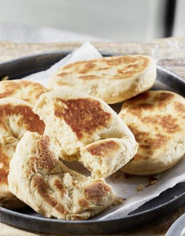 Naan-Brot mit Raita auf einem schwarzen Teller, daneben Raita-Dip