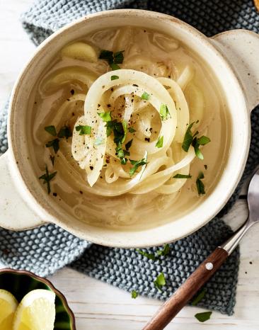 Schnelle Zwiebelsuppe in einer Schüssel, daneben ein Löffel.