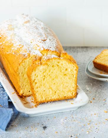 Angeschnittener Eierlikörkuchen aus der Kastenform mit Puderzucker.