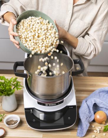 Brötchenwürfel werden in den Cookit gegeben.