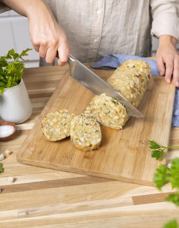Semmelknödel wird in Scheiben geschnitten.