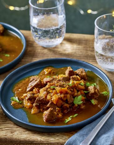 Entenragout auf einem blauen Teller angerichtet, Lichterkette im Hintergrund