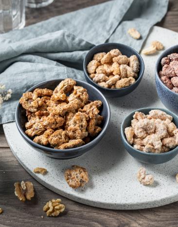 Vier verschiedene gebrannte Nüsse in Schälchen.