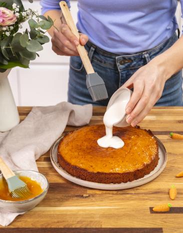 Karottenkuchen wird mit Zuckerguss bestrichen.