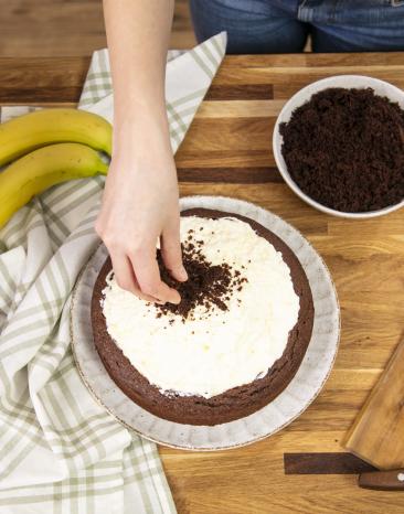 Kuchenkrümel werden auf Sahnepudding gegeben für Maulwurfkuchen.