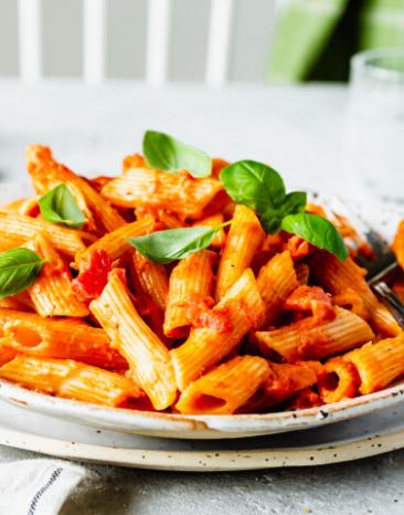 One-Pot-Pasta mit Tomaten-Curry-Sauce in einem weißen Teller serviert.