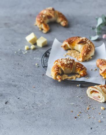 Schinken-Käse-Croissants auf einem Kuchengitter mit Backpapier.