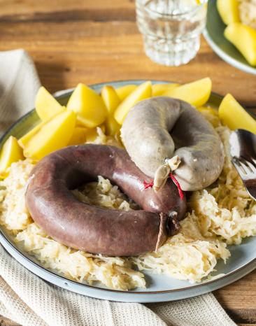 Schlachtplatte mit Blut-und Leberwurst Salzkartoffeln und Sauerkraut auf einem Teller.