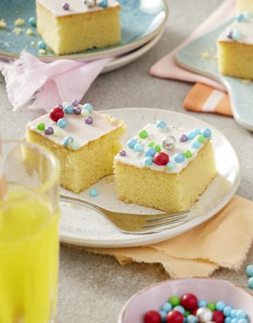 Veganer Fantakuchen vom Blech mit bunten Perlen in Stücke geschnitten.