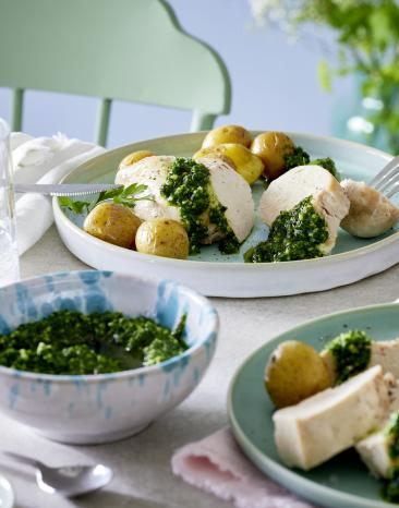 Neue Kartoffeln mit Hähnchen und Pesto auf Tellern.
