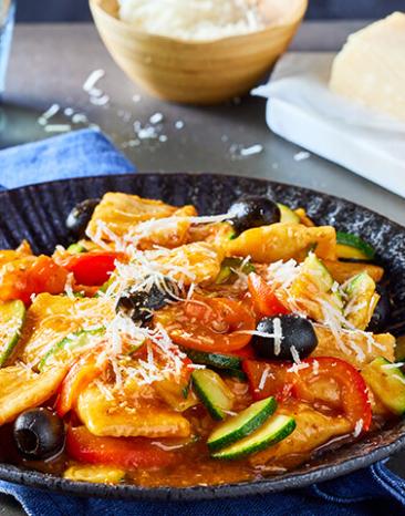 Ravioli mit Gemüse auf einem dunklen Teller.