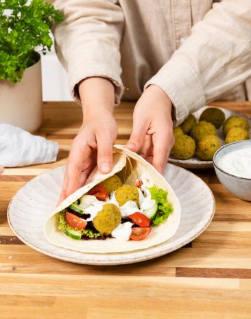 Falafel mit Gemüse und Dip in einem Wrap genießen.