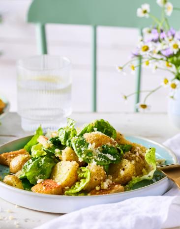 Caesar salad in Schüsseln auf einem gedeckten Tisch mit Blumen.