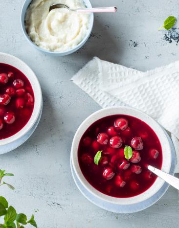 Kirschsuppe mit ganzen Kirschen und Minzblatt.