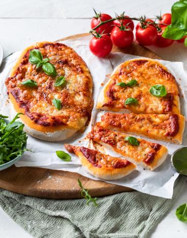 Pinsa belegt mit Tomatensauce, Käse und Basilikum.