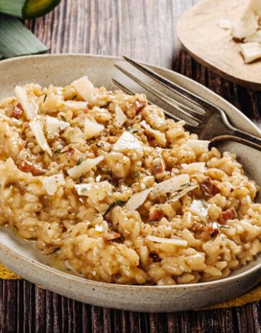 Risotto mit Speck und Lauch in einem hellen Teller.