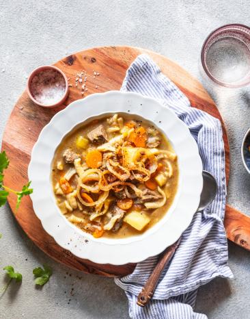 Gaisburger Marsch in einem tiefen Teller, daneben Kräuter.