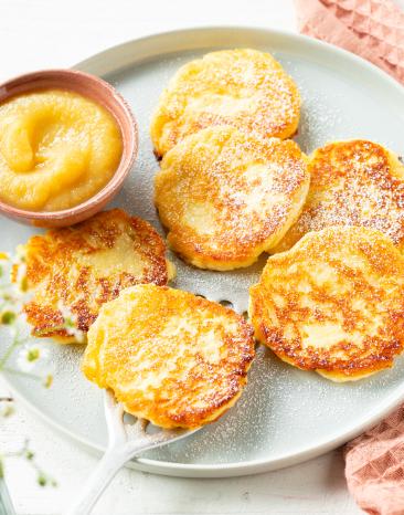 Quarkkeulchen mit Apfelmus auf einem Teller.