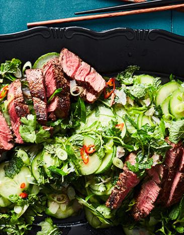 Thailändischer Rindfleischsalat in einer schwarzen Schale mit Essstäbchen.