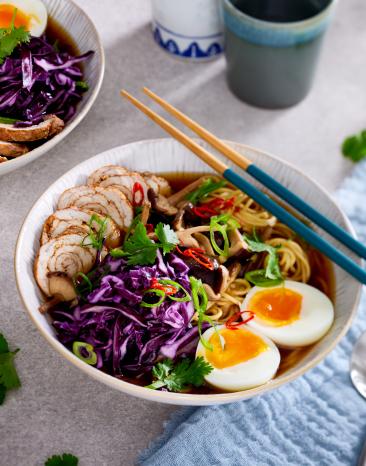 Pinke Ramen in Schüsseln mit Gemüse und Eiern.
