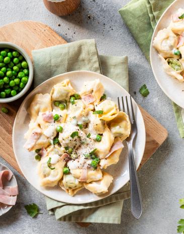 Tortellini mit Schinken und Erbsen auf Teller