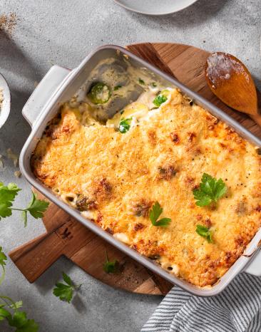 Rosenkohl-Kartoffel-Auflauf in einer hellen Form mit Petersilie getoppt.