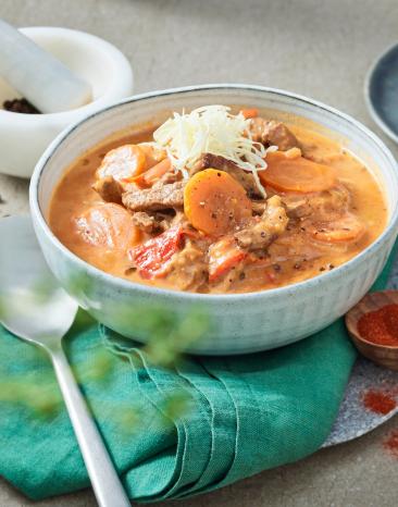 Rouladen Topf mit Gemüse in einem tiefen Teller auf einem Tisch.