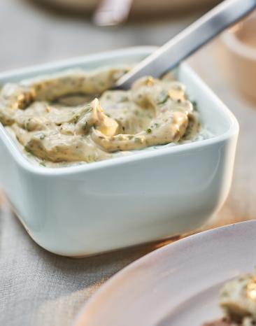 Remoulade in einer kleinen weißen Schale mit Löffel.