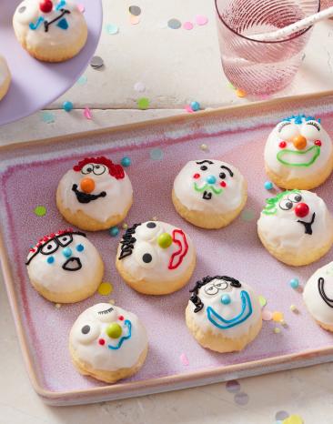 Berliner aus dem Backofen mit bunten Clownsgesichtern.