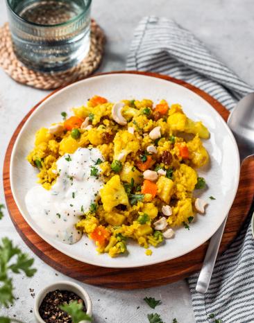 Vegetarisches Bryani mit buntem Gemüse und Reis auf einem hellen Teller.