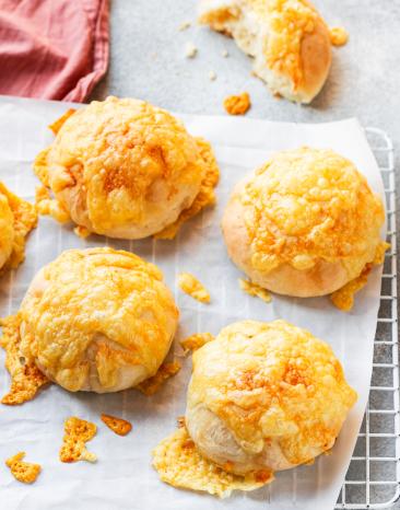 Käsebrötchen mit knuspriger Käsekruste auf einer Platte mit Tuch.