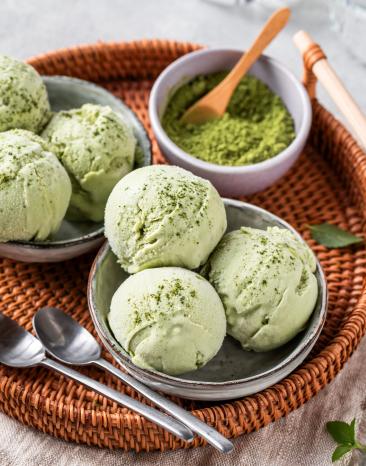 Matcha Eis Kugeln in Schälchen mit Matcha Pulver.