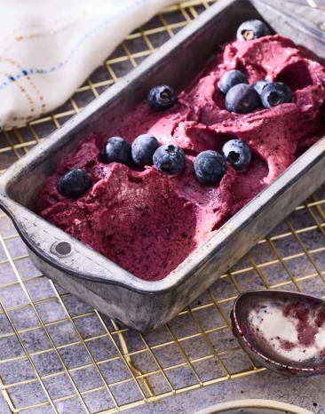 Blaubeer-Joghurt-Nicecream mit frischen Beeren garniert.