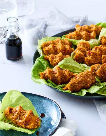 Vegane Cig Köfte in Salatblättern auf einem Teller.