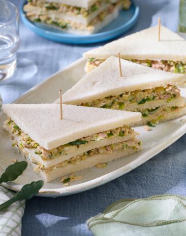 Tramezzini mit Thunfisch mit Holzspießen auf einem Servierteller.